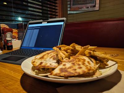 a quesadilla burger and a laptop sitting on the table at a restaurant
